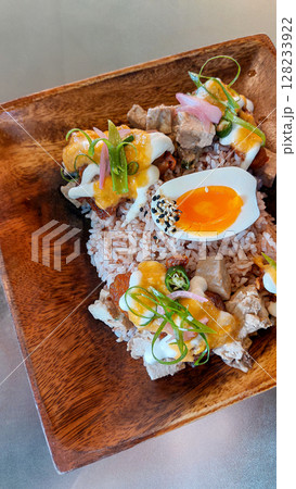 A wooden plate filled with brown rice, topped with tofu cubes, halved boiled egg and various colorful garnishes, creating a fresh and vibrant look for a healthy vegetarian meal A wooden plate filled with brown rice, topped with tofu cubes, halved boiled egg and various colorful garnishes, creating a fresh and vibrant look for a healthy vegetarian meal 128233922