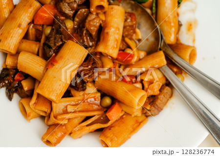 Delicious pasta with beef stew and vegetables being mixed with silver cutlery 128236774