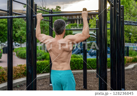Muscular man sportsman with strong back muscle. Sport pullup workout. Sport training. Man sportsman do pullup exercise. Muscular biceps and triceps. Strong athlete. Man pullup at outdoor gym 128236845