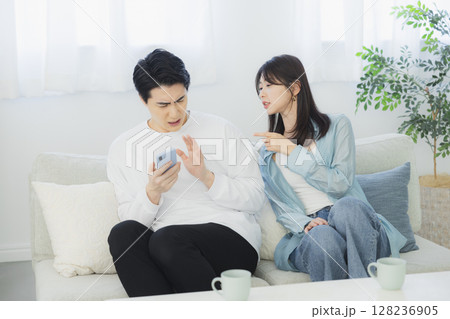 リビングでスマホを見る若い夫婦　 128236905