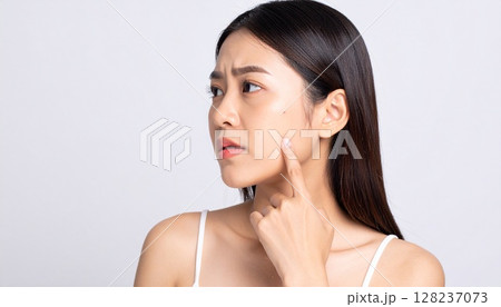 すっぴん女性の肌悩みのイメージ。頬にできたニキビに悩む女性の顔アップ。 128237073