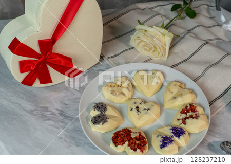 Heart-shaped white chocolate treats with red ribbon gift box and white rose 128237210