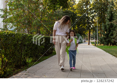 Mother and daughter walking together in a park on a sunny day Mother and daughter walking together in a park on a sunny day 128237242