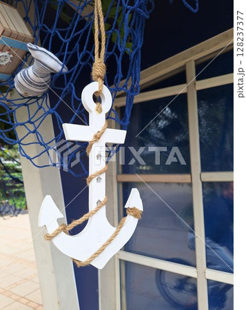 Nautical decor with white anchor on blue fishing net background Nautical decor with white anchor on blue fishing net background 128237377
