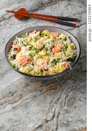 Stir fry rice with salmon, egg, green peas, onion and seaweed close-up in bowl. Vertical Stir fry rice with salmon, egg, green peas, onion and seaweed close-up in bowl. Vertical 128238864