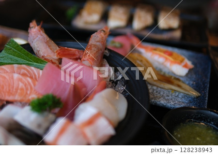 A beautifully arranged sushi platter features colorful slices of sashimi, including salmon, tuna, and octopus, adorned with fresh greens. This culinary delight reflects Japanese cuisine's artistry. 128238943