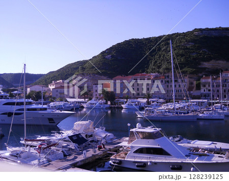 Stunning panoramic view of Bonifacio, a luxurious seaside resort in Carsica, France. The image features a picturesque harbor filled with elegant white yachts. 128239125