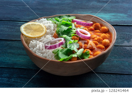 Chana masala, chickpea curry, traditional Indian dish, on a dark wooden table Chana masala, chickpea curry, traditional Indian dish, on a dark wooden table 128241464