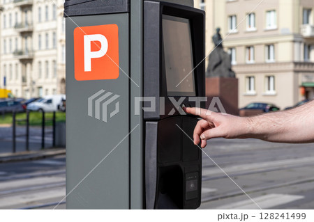 Human hand operates a modern city parking meter displaying an orange P sign for street payment, emphasizing urban mobility and efficient public service technology Human hand operates a modern city parking meter displaying an orange P sign for street payment, emphasizing urban mobility and efficient public service technology 128241499