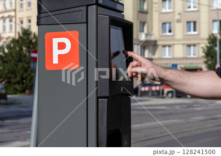 User's hand interacts with a smart digital parking payment machine, prominently displaying a white P symbol, facilitating efficient urban mobility and modern city service access User's hand interacts with a smart digital parking payment machine, prominently displaying a white P symbol, facilitating efficient urban mobility and modern city service access 128241500