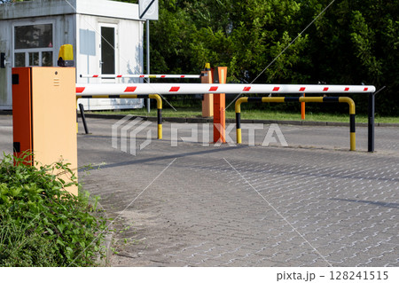 Automated parking barrier with a lowered arm and security booth, effectively managing vehicle access and site security at an an entry point Automated parking barrier with a lowered arm and security booth, effectively managing vehicle access and site security at an an entry point 128241515