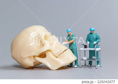 Miniature Surgeons Operating on Human Skull Model Miniature Surgeons Operating on Human Skull Model 128242877