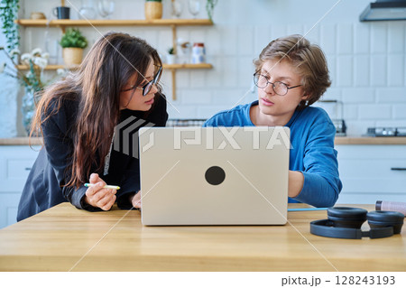 Teenage boy student with female mentor trainer teacher looking at laptop computer screen Teenage boy student with female mentor trainer teacher looking at laptop computer screen 128243193