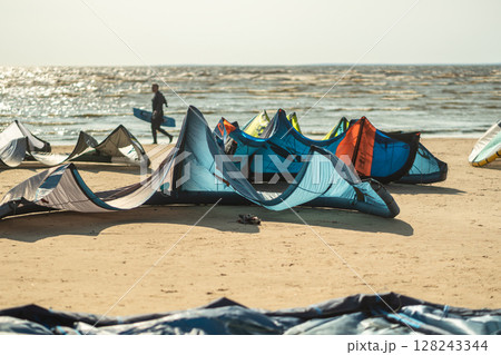 Kite surfing event at seaside beach with multicolored sails and boards. Summer activity in travel Kite surfing event at seaside beach with multicolored sails and boards. Summer activity in travel 128243344