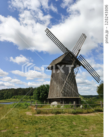 An old wooden windmill on a summer day. Mikhailovskoye Estate. Pushkin Hills, Russia. Landmark, vertical photo. An old wooden windmill on a summer day. Mikhailovskoye Estate. Pushkin Hills, Russia. Landmark, vertical photo. 128243806