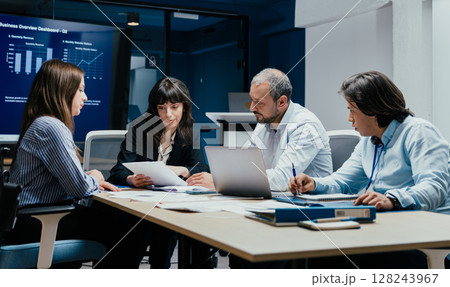 Business executives and assistants brainstorming investment risk evaluation in corporate boardroom 128243967