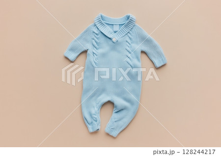 Baby knitted onesie on beige background. Fashion newborn clothes. Flat lay top view. Wool kid soft clothing. Infant trendy bodysuit made of organic eco friendly cotton. Children wardrobe. Baby garment 128244217