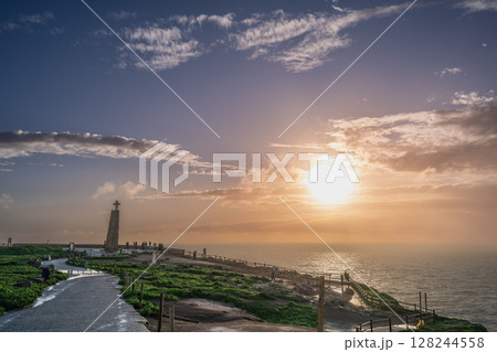 Sunset at Cabo de Roca with Iconic Cross Overlooking Ocean Horizon. 128244558