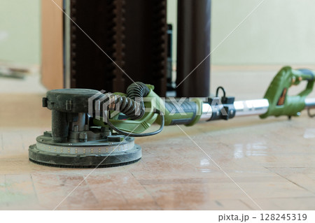 Floor Sanding Process with Green Drywall Sander, Dust Extraction Hose, and Polished Marble Tile Flooring in Home Renovation Project Floor Sanding Process with Green Drywall Sander, Dust Extraction Hose, and Polished Marble Tile Flooring in Home Renovation Project 128245319