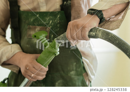 Marine Servicing Equipment with Green Hose and Nozzle, Military Maintenance Task, Camouflage Uniform, Digital Watch, Olive Drab Tone. Marine Servicing Equipment with Green Hose and Nozzle, Military Maintenance Task, Camouflage Uniform, Digital Watch, Olive Drab Tone. 128245338