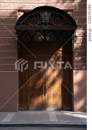 A beautifully crafted Elegant Wooden Door adorned with Exquisite Intricate Ironwork detailing 128245380