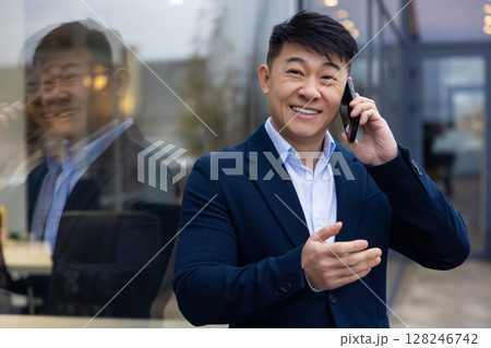 Young asian man in a suit with a phone in hand Young asian man in a suit with a phone in hand 128246742