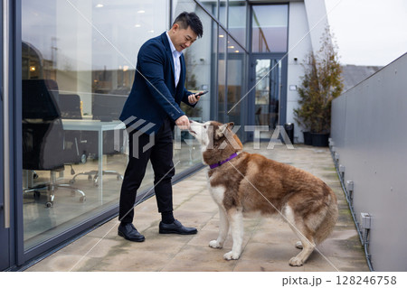 Young man playing with a dog near the office and looking contented 128246758