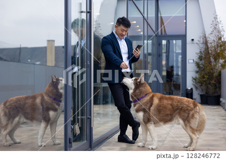 Young man in a suit standing near the business center entrance with a dog next to him Young man in a suit standing near the business center entrance with a dog next to him 128246772