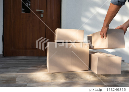 Close up of mans hand taking boxes while moving to the new house Close up of mans hand taking boxes while moving to the new house 128246836