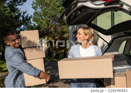 Young couple carrying boxes to the car while moving to a new house 128246881