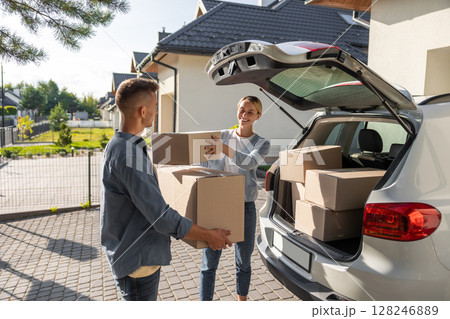 Young couple packing clothes into boxes and getting prepared for the moving in Young couple packing clothes into boxes and getting prepared for the moving in 128246889