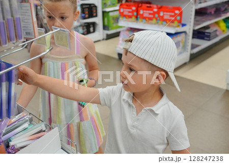 Brother and sister choose school accessories for school at the market 128247238