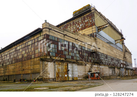 Abandoned factory with rusty metal panels and weathered concrete exterior 128247274