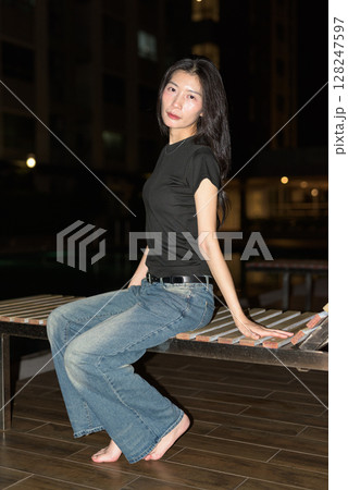 Portrait of beautiful Asian woman at night at pool during holiday 128247597