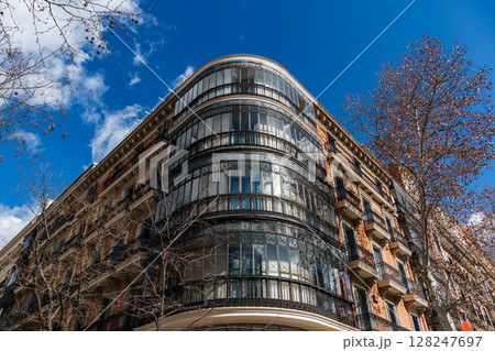 An architectural marvel with curved glass facade graces a street in Madrid under a bright sky. An architectural marvel with curved glass facade graces a street in Madrid under a bright sky. 128247697