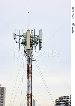Wireless Communication Antenna pole, Mobile phone mast antenna pole on top of dilapidated building 128248010