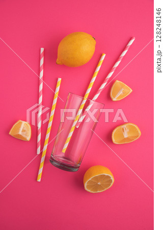 Preparing lemonade. Lemons, straws, and a glass on a vibrant pink background. 128248146