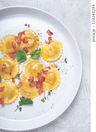 fresh ravioli, with butter, spices and herbs, fried bacon, on the table, top view, light background, no people, 128248284