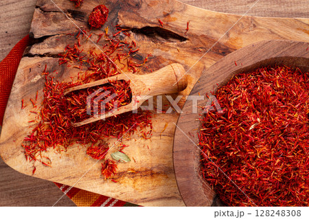 Spice saffron threads, in a wooden bowl, on a wooden table, top view, close-up, Spice saffron threads, in a wooden bowl, on a wooden table, top view, close-up, 128248308