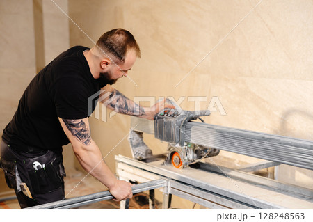 Construction worker cutting ceramic tiles using professional machine 128248563
