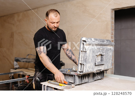 Construction worker taking hammer from toolbox during renovation works Construction worker taking hammer from toolbox during renovation works 128248570