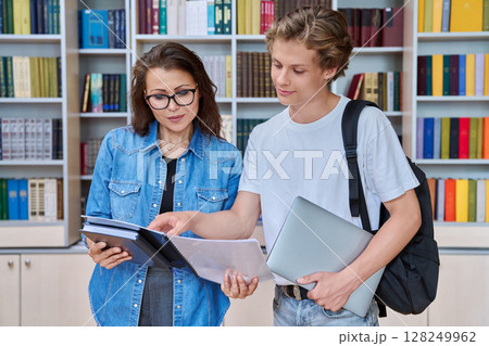 Teenage guy student meeting discussing with female teacher in library Teenage guy student meeting discussing with female teacher in library 128249962