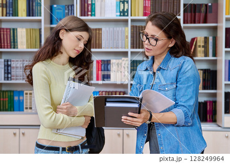 High school student girl teenager meeting discussing with teacher mentor in classroom 128249964