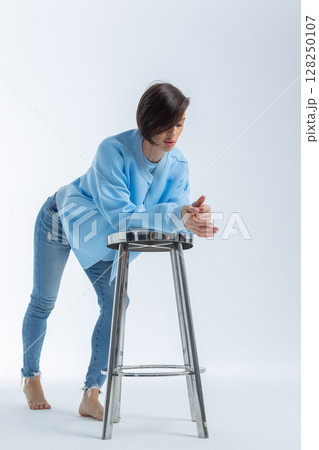 Beautiful woman of model appearance. Girl in blue clothes on grey background. Pretty female with trendy makeup posing in studio. Vertical photo. High quality photo Beautiful woman of model appearance. Girl in blue clothes on grey background. Pretty female with trendy makeup posing in studio. Vertical photo. High quality photo 128250107