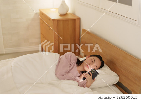 夜ベッドでスマホを使う女性 128250613