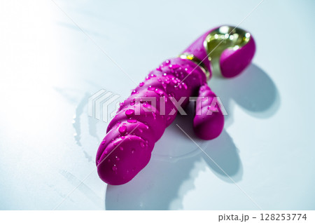 Wet Magenta colored ribbed vibrator in water. Wet Magenta colored ribbed vibrator in water. 128253774