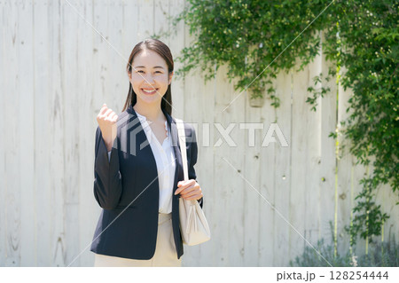 白い塀の前にいるスーツの女性 白い塀の前にいるスーツの女性 128254444