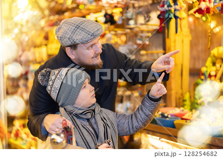 Man with son in outdoor souvenir shop examines Christmas toys 128254682