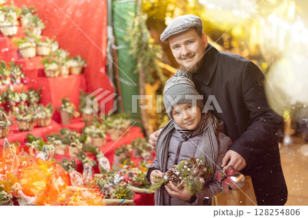 During Christmas fair, father and son choose composition, bouquet of fir branches, eucalyptus shoots During Christmas fair, father and son choose composition, bouquet of fir branches, eucalyptus shoots 128254806