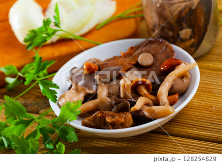Various pickled mushrooms in plate with onions and parsley closeup Various pickled mushrooms in plate with onions and parsley closeup 128254829